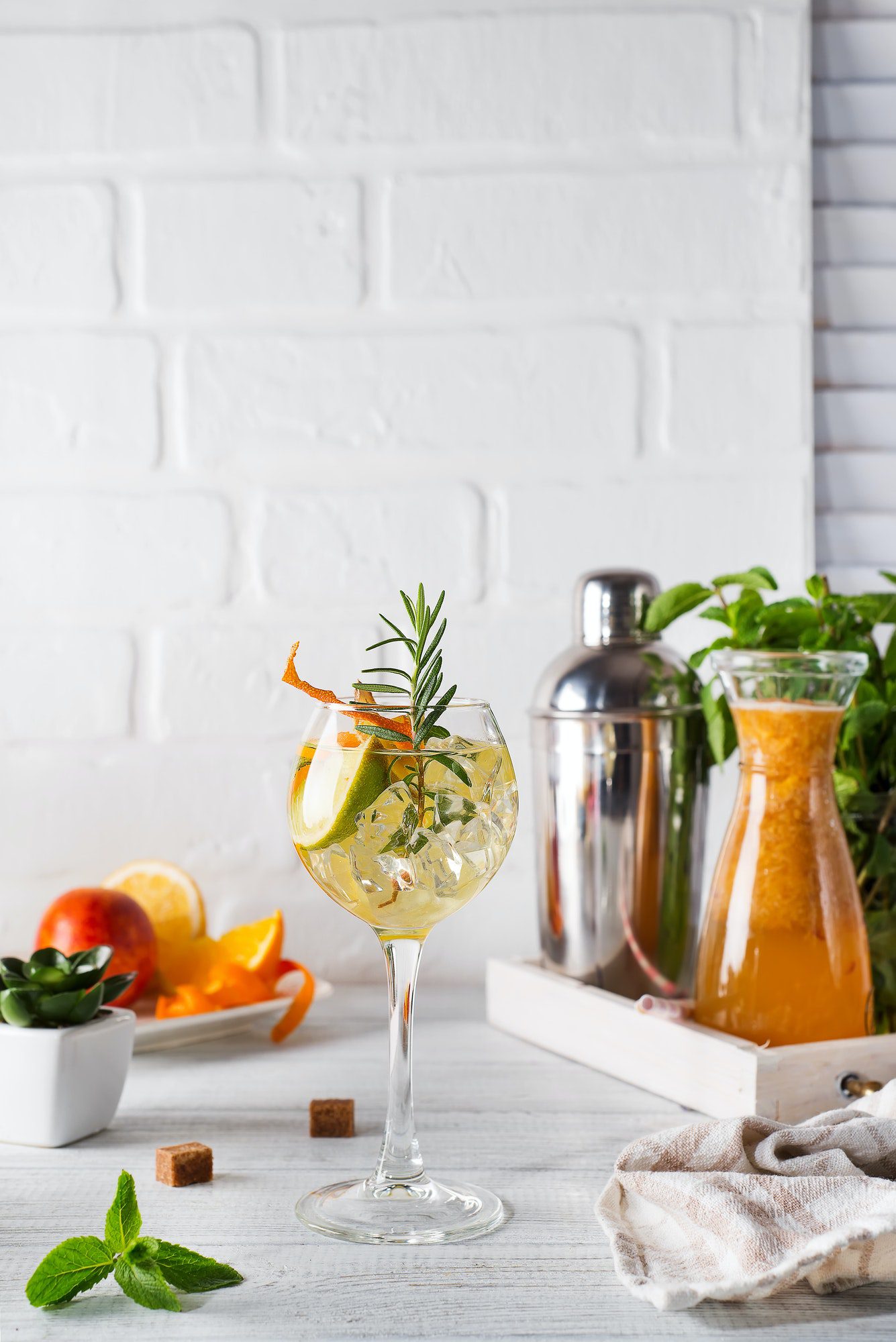 Fresh mojito drink with rosemary, lemon and orange on white wooden backgorund, copy space